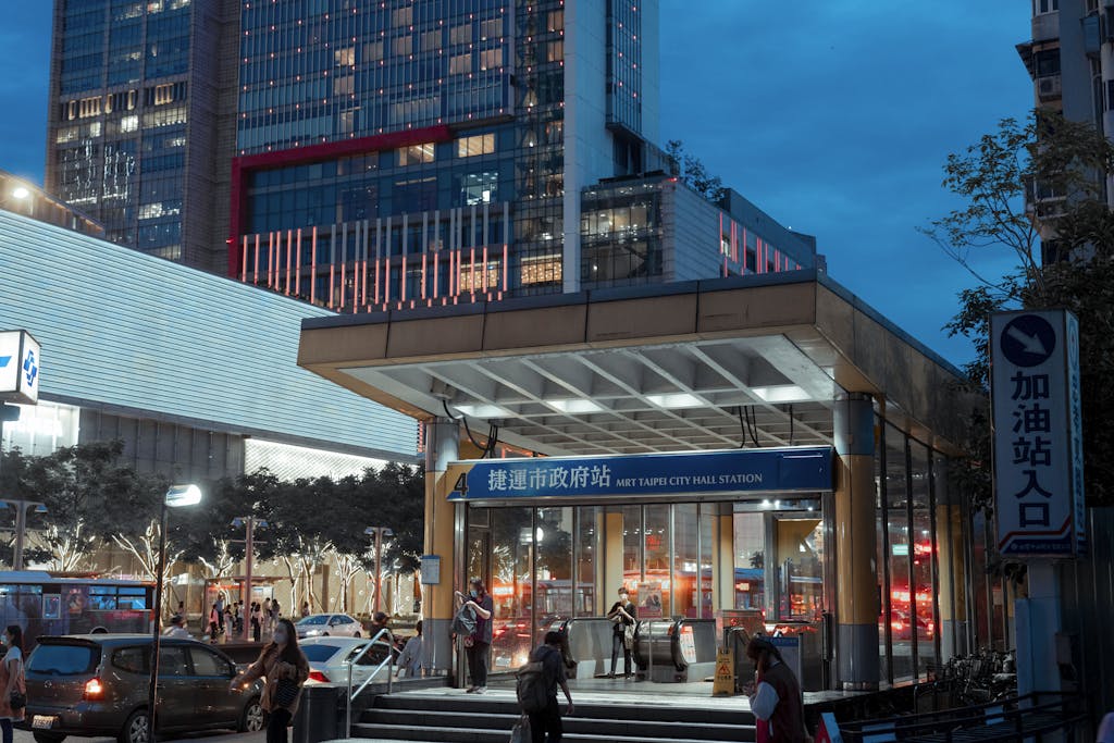 Bustling MRT entrance in Taipei at night, with urban city life and illuminated architecture.