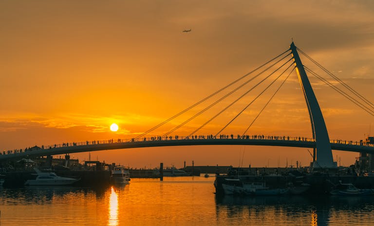 Silhouettes of people on Lovers Bridge at sunset in Tamsui, Taiwan.