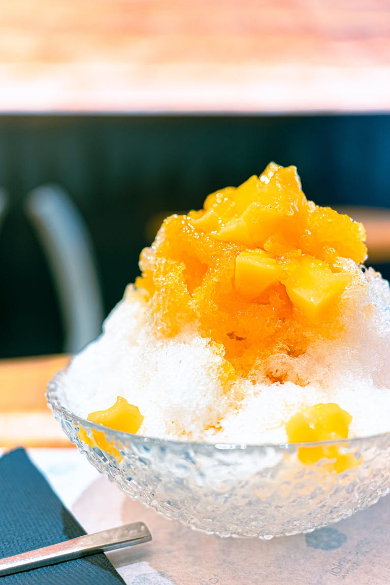 Close-up of mango shaved ice in a glass bowl, perfect summer treat.